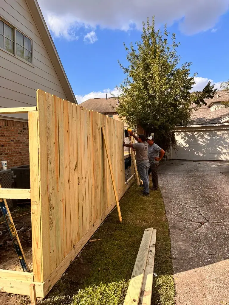 Construcción de cerca de madera junto a una casa.